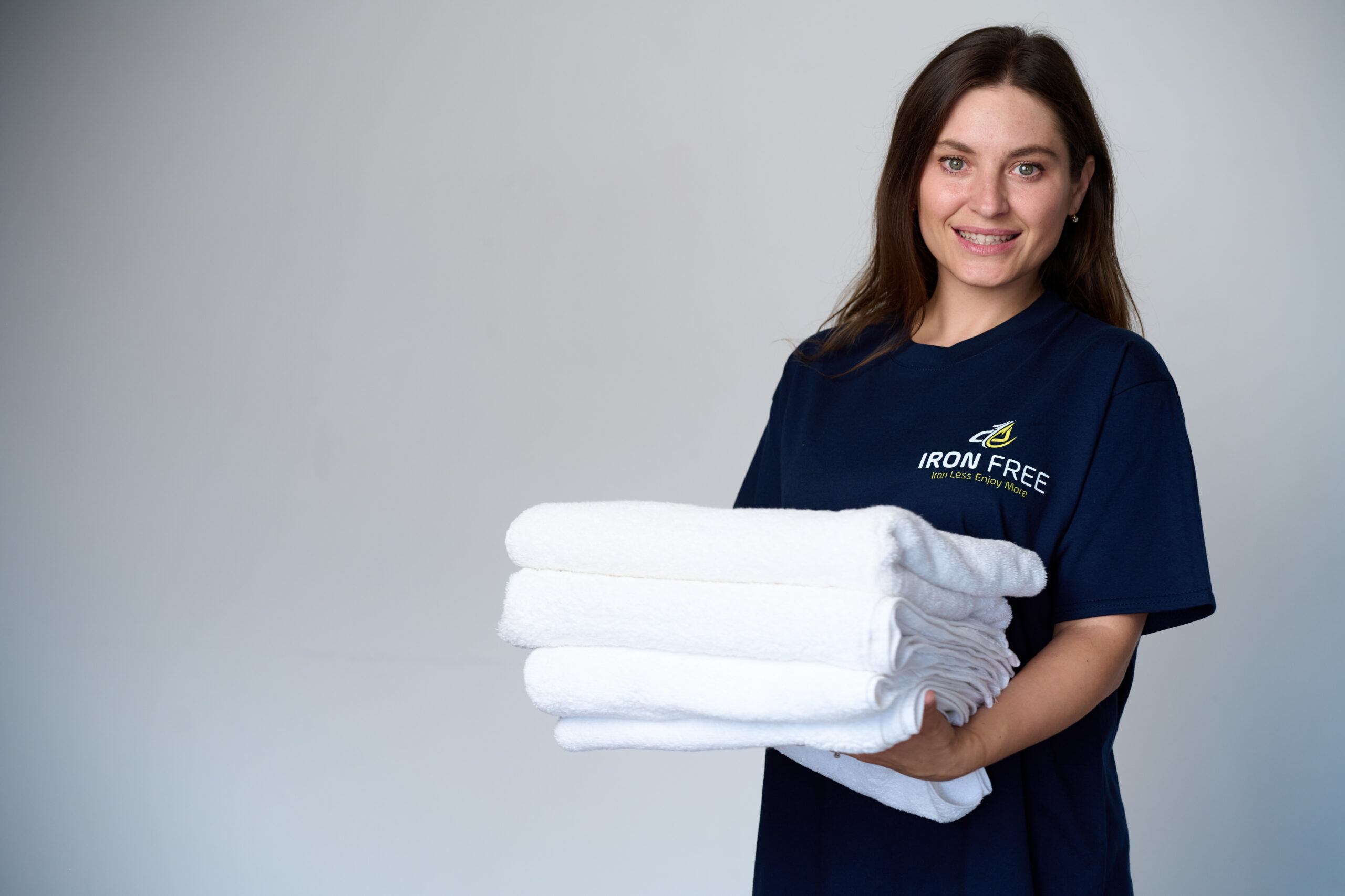 Iron Free team member holding freshly folded linen and towels